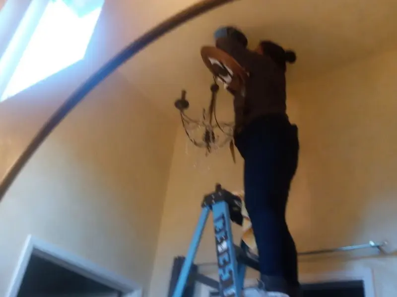 Electrician installing a chandelier in a Red Bank residence